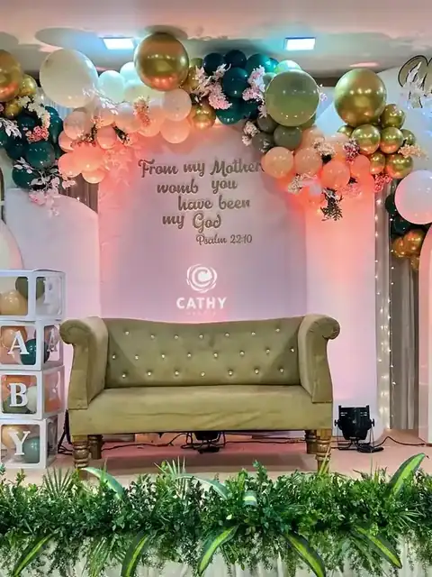 Baby shower stage with butterfly wings, balloons and a sofa